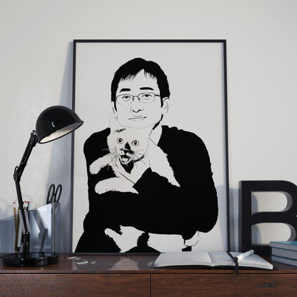 black and white framed illustration of horror manga artist Junji Ito holding a black and white cat, frame is on a desk with a black lamp and large letter B